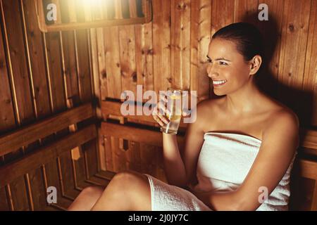 Profiter de sa séance avec le sauna. Petit cliché d'une jeune femme qui se détend au sauna dans un spa. Banque D'Images