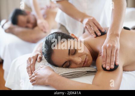 Thérapie aux pierres chaudes pour une relaxation musculaire plus profonde. Photo d'un couple mature bénéficiant d'un traitement aux pierres chaudes. Banque D'Images