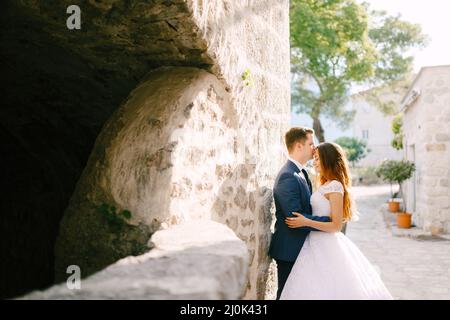 La mariée et le marié embrassent sur une belle vieille rue de Perast, le marié embrasse la mariée sur le front Banque D'Images