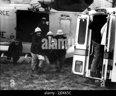 Un RAF recherche et sauvetage Sea King de RAF Boulmer terres un homme, qui a été arraché hors de la mer au large de Cullercoats. Les pompiers transportent un blessé dans une ambulance en attente. L'hélicoptère avait été impliqué dans le double sauvetage en cas de vents forts qui avait commencé avec un chavirement de bateau de pêche suivi d'un bateau de sauvetage faisant de même. Deux hommes ont été sauvés par le Sea King, un autre homme a réussi à nager de nouveau vers le rivage un quatrième noyé piégé par les algues et la corde du bateau. 22/02/1981. Banque D'Images