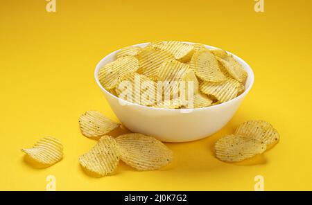 Croustilles striées dans un bol sur fond jaune Banque D'Images