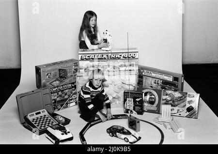 Un jeune garçon et une fille avec une sélection de jouets pour enfants pour Noël. Décembre 1980. Banque D'Images