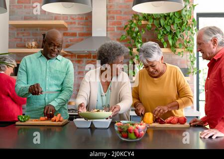 Groupe d'amis hommes et femmes de haut niveau et variés qui cuisent ensemble à la maison Banque D'Images