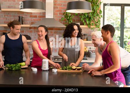 Groupe d'amis de sexe féminin et masculin divers préparant du smoothie ensemble dans la cuisine Banque D'Images