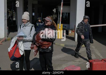 19 mars 2022, Siret, Roumanie : une famille traverse la frontière entre la Roumanie et l'Ukraine. Environ 3 mille personnes arrivent quotidiennement à Siret, en Roumanie, pour se réfugier contre la violence causée par la guerre entre la Russie et l'Ukraine. Dans cette ville frontalière, un couloir d'aide humanitaire a été organisé entre diverses organisations civiles et étatiques. Les personnes qui fuient l'Ukraine sont principalement des femmes, des enfants et des adultes plus âgés. Lorsqu'ils franchissent la frontière, les gens reçoivent de l'aide médicale, psychologique, alimentaire, de transport et d'hébergement. Grâce à l'aide des bénévoles, ces gens peuvent prendre une pause et gagner de la force Banque D'Images