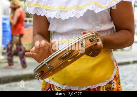 Femme en vêtements ethniques colorés jouant du tambourin Banque D'Images