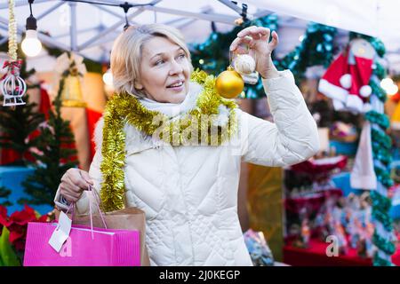 Bonne femme mûre en guirlande avec des jouets de Noël à la foire Banque D'Images