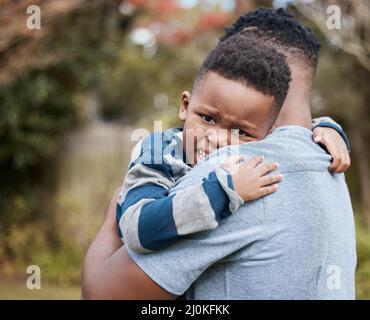 SHH, theres pas besoin de pleurer. Photo d'un père méconnaissable réconfortant son fils tout en le liant avec lui dans le jardin. Banque D'Images