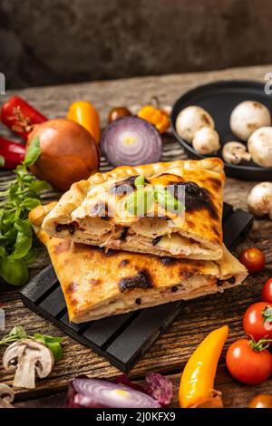 Pizza en tranches calzone servie sur une palette noire Banque D'Images