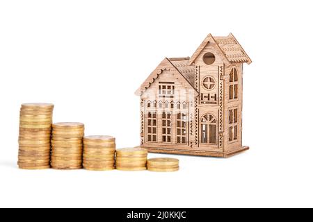 maison en bois et piles de pièces isolées sur fond blanc Banque D'Images