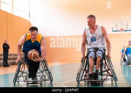 Les vétérans handicapés de guerre ou de travail ont mélangé des équipes de basket-ball de race et d'âge en fauteuil roulant jouant un match d'entraînement dans une salle de sport. Banque D'Images