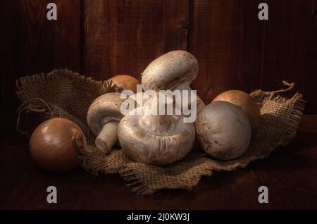 Champignons sur une serviette en toile de jute sur fond de bois sombre dans un style rustique Banque D'Images