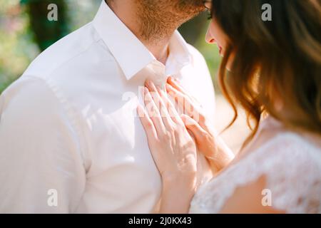 Le marié embrasse doucement la mariée sur le front, la mariée met ses mains sur la poitrine du marié Banque D'Images