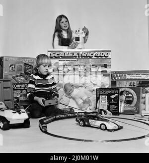 Un jeune garçon et une fille avec une sélection de jouets pour enfants pour Noël. Décembre 1980. Banque D'Images