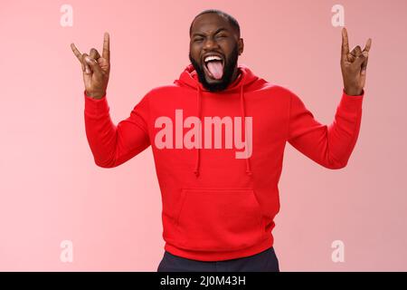 Rebelle sortant bon-look énergique afro-américain barbu homme ayant plaisir de faire la fête montre de métal lourd rock-n-roll gestur Banque D'Images