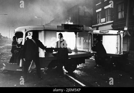 Toxteth Riot 6th juillet 1981Police les officiers tentent de nettoyer un bloc de flotteurs de lait sur Park Road afin que les pompiers puissent contrôler l'incendie qui fait rage dans les magasins pillés plus loin sur la route. Les émeutes ont été déclenchée à la suite de l'interception par la police des motocyclistes Leroy Cooper, dans la rue Selbourne. Une foule s'est rassemblée, les noms se sont multipliés par des plaisanteries et en quelques minutes, il y avait une fracture à grande échelle qui a vu trois policiers blesser et un jeune homme local, arrêté pour voies de fait. Cela ne s'est pas arrêté là. La police a monté des patrouilles supplémentaires dans la région et, tôt le soir suivant, le 4 juillet, ils sont entrés en service Banque D'Images