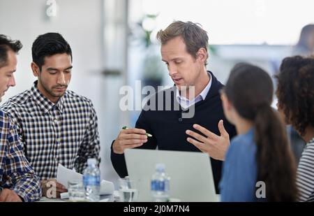 S'assurer que tout est logique pour le personnel. Groupe de collègues assis autour d'une table de réunion ayant une discussion sérieuse. Banque D'Images