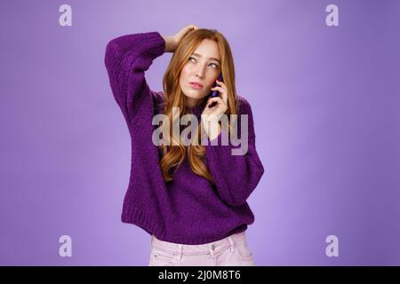 Une femme adorable et mignonne à faire une nomination par téléphone portable en se grattant la tête et en se calant, en regardant comme ma pensée Banque D'Images