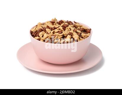 Cornflakes au chocolat et au miel dans une assiette rose sur fond blanc. Petit déjeuner avec lait Banque D'Images