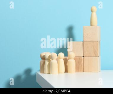 La figurine en bois d'un homme se tient sur un haut podium de cubes, sous la foule. Recherche d'employés talentueux, rallye, manipulation o Banque D'Images