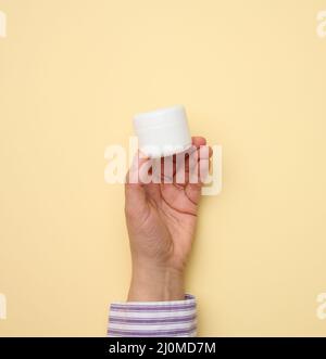 Main femelle tenant le bol en plastique blanc. Emballage pour la crème, le gel, le sérum, la publicité et la promotion des produits Banque D'Images