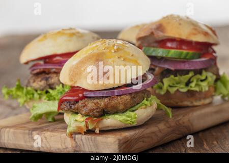 Quatre petits hamburgers sur une planche Banque D'Images