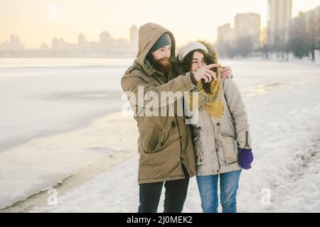 Thème amour et date sur la nature. Un jeune homme de couple hétérosexuel caucasien et une jeune fille marchent en hiver le long d'un lac gelé en wint Banque D'Images