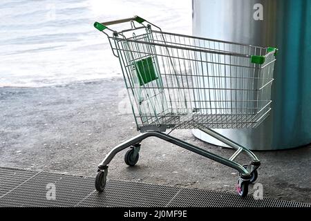 Un panier vide se trouve devant l'entrée du centre commercial Banque D'Images