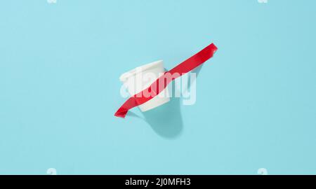 Gobelet en carton blanc collé avec du ruban adhésif rouge sur le fond bleu Banque D'Images