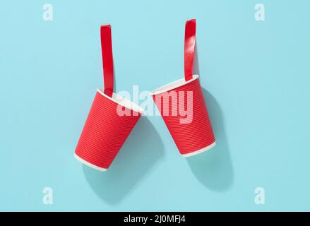 Gobelet en carton rouge collé avec du ruban adhésif rouge sur le fond bleu Banque D'Images