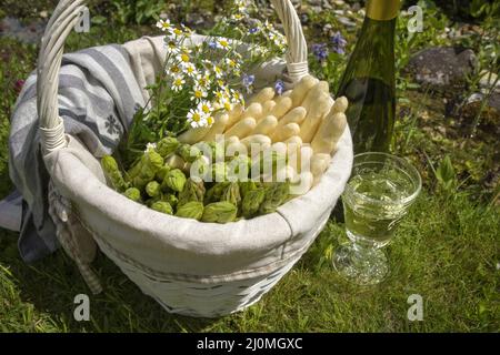 Asperges fraîches, blanches et vertes, crues offertes en gros plan dans un panier extérieur dans l'herbe Banque D'Images