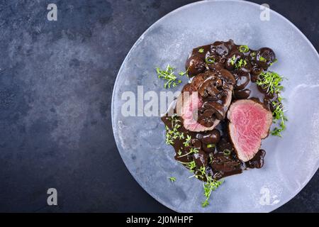 Style moderne traditionnel frit et sec filet de bœuf angus medaillons naturels aux champignons dans une sauce au vin rouge servi comme vue de dessus Banque D'Images