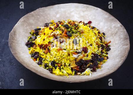 Traditionnel persan tahdig jeweled javaher polow mariée riz basmati avec fruits secs et baies servi comme gros plan sur un rustique Banque D'Images