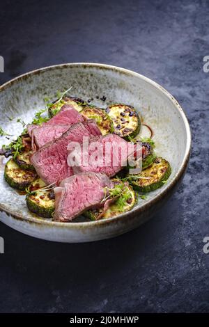 Des medaillons de filet de bœuf angus frits et séchés avec courgettes et cresson de style moderne sont servis en gros plan dans un style nordique Banque D'Images
