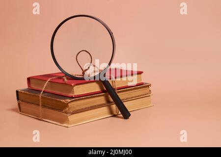 Une pile de vieux livres battus attaché avec une corde de jute et une loupe Banque D'Images