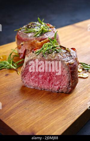Style moderne traditionnel frit et sec filets de bœuf angus médaillons naturellement enveloppés de bacon et servis sur un boa en bois Banque D'Images