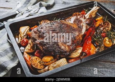 Épaule d'agneau traditionnelle au barbecue avec légumes et piment servi en gros plan sur un plateau métallique rustique Banque D'Images