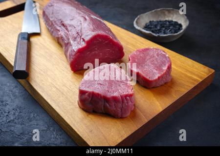 Filet de bœuf cru traditionnel, steak naturel au sel noir, en gros plan sur un panneau en bois de conception moderne Banque D'Images