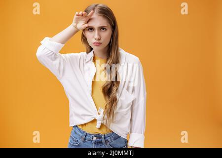 Mal facile, sombre et bouleversé jolie femme avec longue coiffure ondulée naturelle tenant la paume sur le front stooping de la tristesse et de l'apathie Banque D'Images