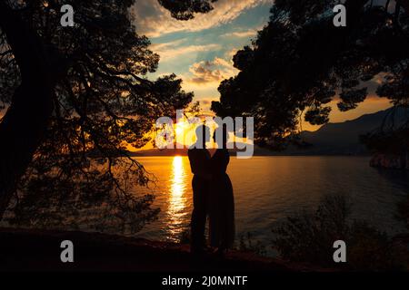 Kotor, Monténégro - 21.06.17: Homme et femme se tiennent sur la mer avec la toile de fond des montagnes au coucher du soleil Banque D'Images