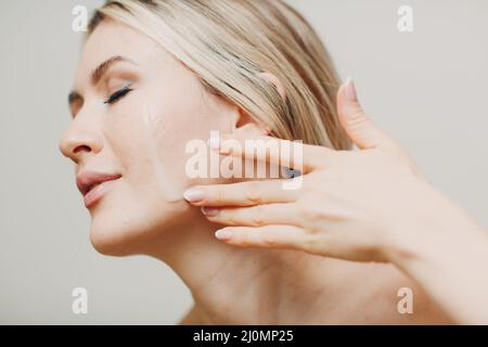 Gelée royale d'huile cosmétique s'appliquant sur le visage de la jeune femme adulte Banque D'Images