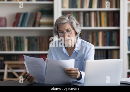 Une femme d'âge moyen sérieuse et réfléchie s'est inquiétée de lire les nouvelles dans un document Banque D'Images