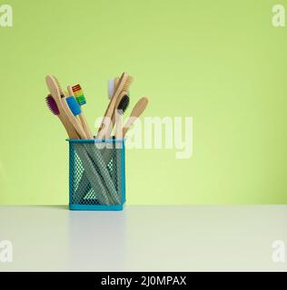 Brosses à dents en bois dans une tasse en plastique sur une table blanche Banque D'Images