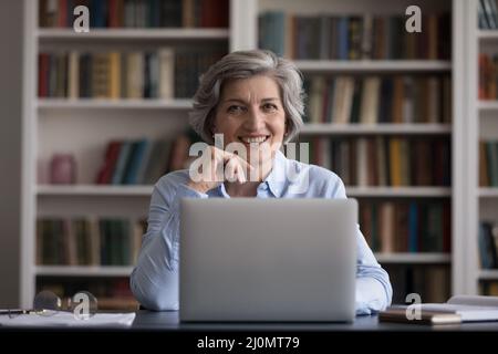 Une femme d'affaires d'âge moyen attrayante travaille assis sur un bureau avec un ordinateur portable Banque D'Images