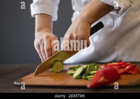 Fermez les mains en coupant le concombre Banque D'Images
