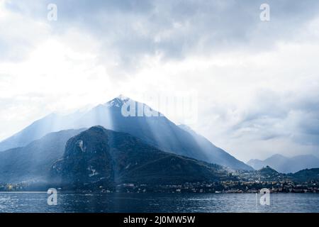 Le soleil brille à travers les nuages au-dessus des sommets de la montagne.Lac de Côme, Italie Banque D'Images