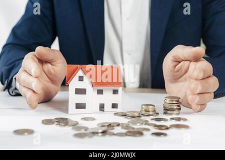 Fermez les mains avec la maison de pièces de monnaie Banque D'Images