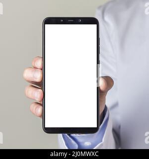 Gros plan de la main d'un médecin montrant un smartphone avec écran blanc Banque D'Images