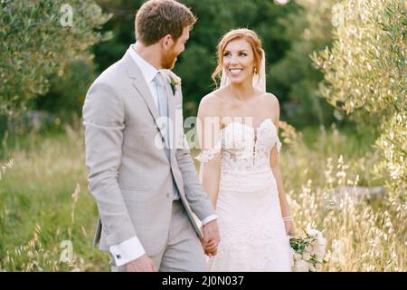 Marié et mariée marchent parmi les arbres dans le parc Banque D'Images