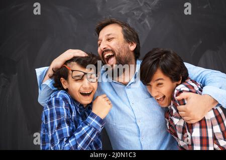 Un père heureux embrassant des fils des moments inoubliables de joie de famille dans la famille arabe moyen-orientale de race mixte Banque D'Images